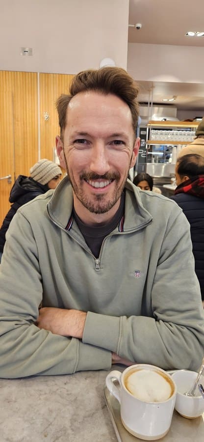 Adam smiling in a coffee shop